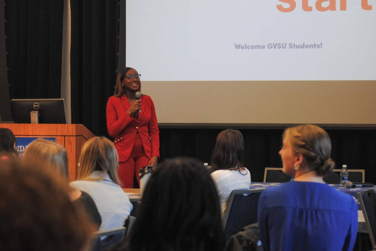 Woman standing at the front of a room speaking into a microphone